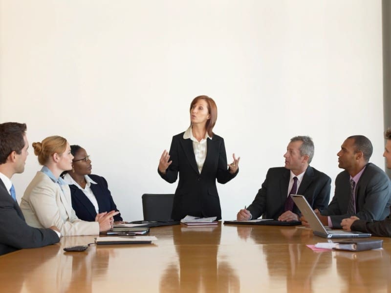 A woman standing at the front of a group of people.