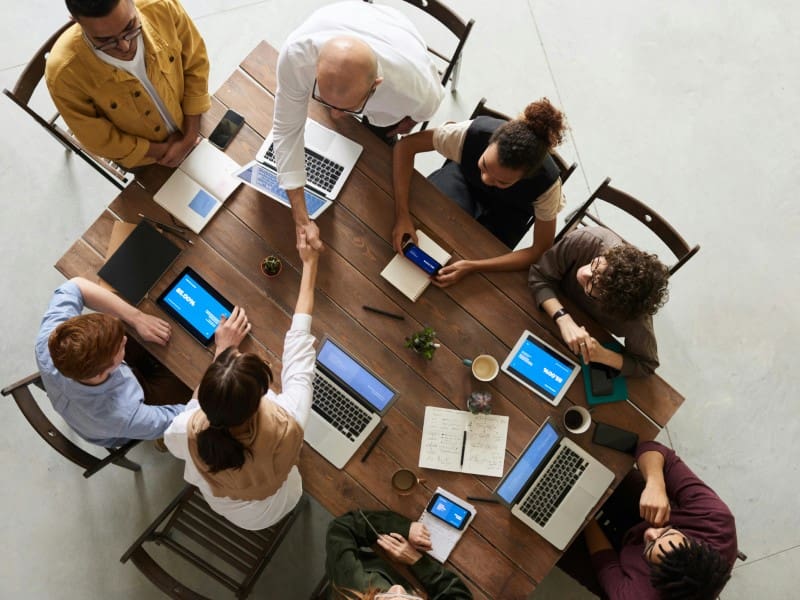 A group of people sitting around a table with laptops.