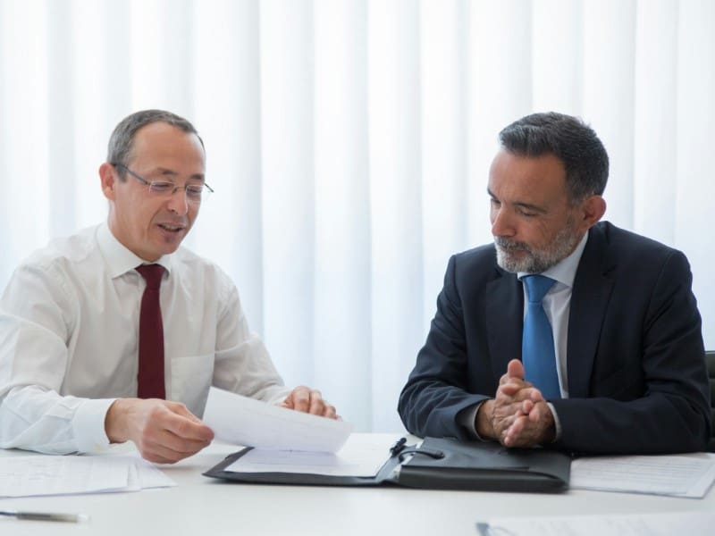 Two men in suits sitting at a table