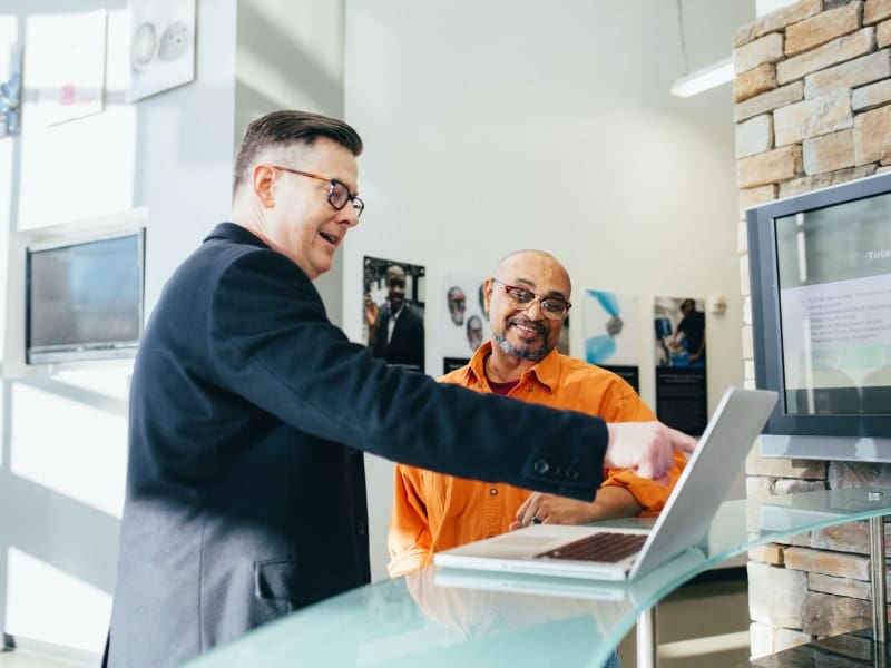 Two men are looking at a laptop together.