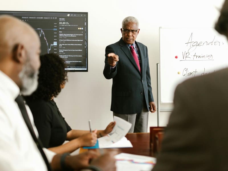 A man in suit and tie standing at the front of a room.